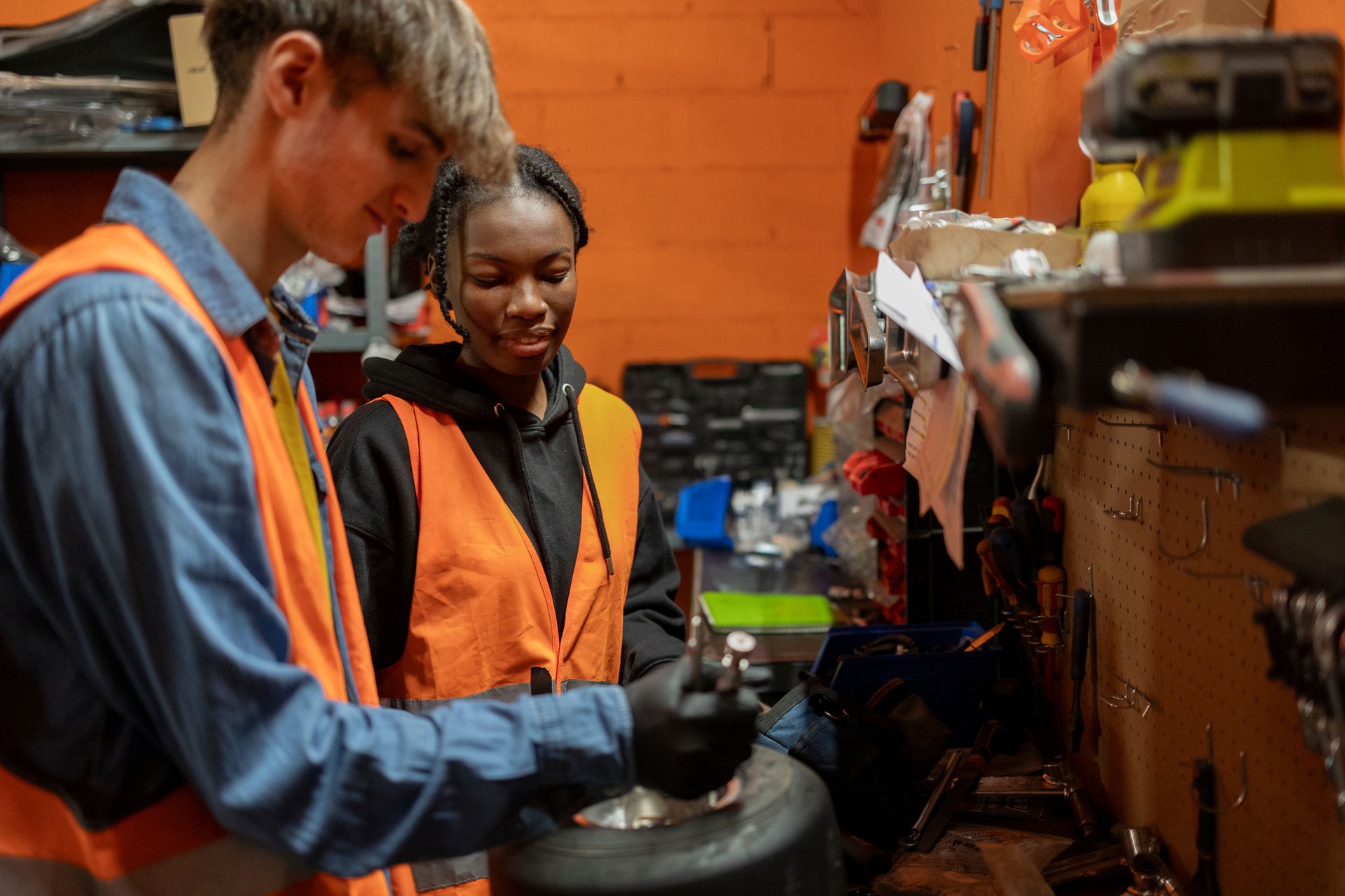 couple of multiracial colleagues working together repairing a wheel in a garage kart mechanic workshop